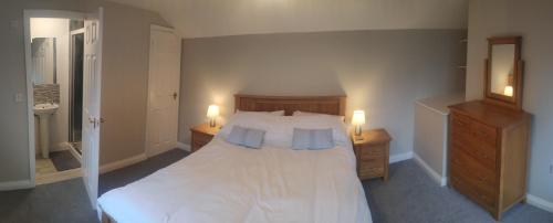欧克汉普敦The Annex Roundaway Lodge的一间卧室配有一张白色床、两个床头柜和两盏灯。