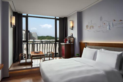 杭州杭州西湖米兰逸扉酒店(步行10分钟至西湖)的一间带大床的卧室和一个阳台