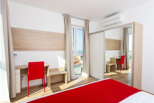 杜布罗夫尼克维拉安科拉公寓的一间卧室配有一张红色的床和一张带红色椅子的桌子