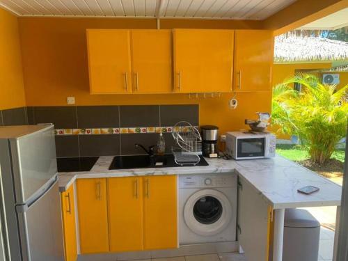大博格Hanamanabungalow Grand-bourg的厨房配有黄色橱柜和洗衣机。
