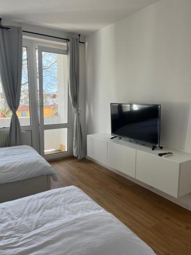 德累斯顿Monteur-& Ferienwohnung Eichmann的白色卧室,白色橱柜上配有平面电视