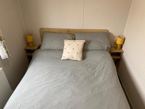 新罗姆尼Cosy holiday home at Romney Sands的一张带两个蓝色枕头和两个黄色蜡烛的床