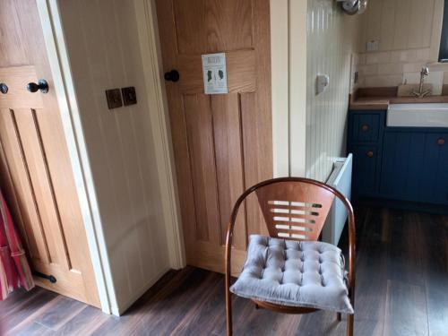 NobberRathgillen Cabin的一把椅子,放在带门的厨房前