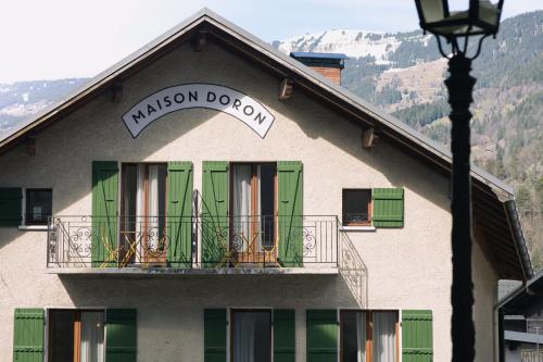 博福特Hôtel Maison Doron的一座带绿门和阳台的建筑