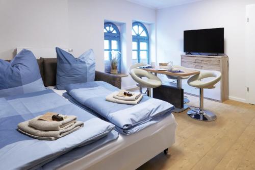 ThallwitzPension "Zum Reußischen Hof"的客房设有两张床、一张桌子和电视。