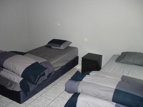 Courcellesappartement Courcelles的一间带两张床的卧室,铺有瓷砖地板。