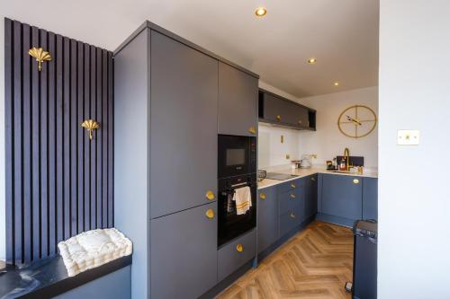 滕比Priory Bay Escapes - Matahari的厨房配有蓝色橱柜和墙上的时钟