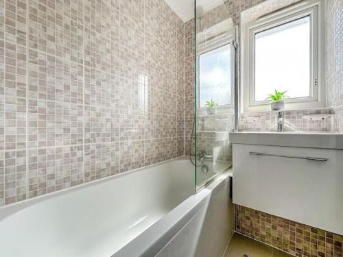 伦敦New Cosy Luxury 3 Bedroom House in Battersea London的白色的浴室设有浴缸和水槽。