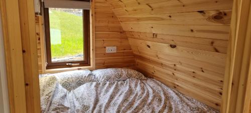 巴利卡斯尔Fairhead Glamping Pods的卧室配有木墙内的一张床