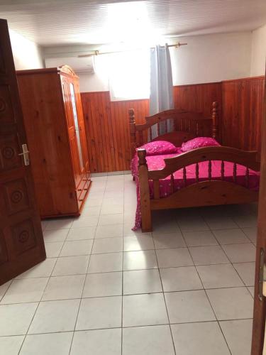 圣安尼Aka Kikine的一间卧室配有一张带粉色床单的木床