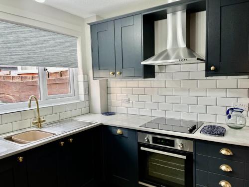 沃灵顿Canada House - Sleeps 6 -3 King or 6 Single Ideal for contractors的厨房配有黑色橱柜、水槽和窗户。
