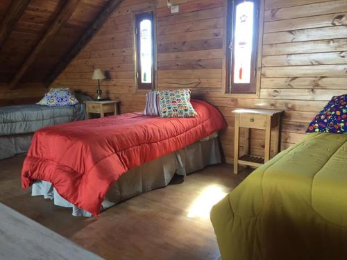 卡皮亚德尔德尔蒙特CABAÑAS ALMA SERENA的小木屋内一间卧室配有红色的床