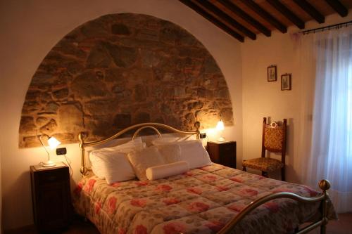 塞吉阿诺安蒂科卡萨莱波祖罗旅馆的一间卧室配有一张石墙床