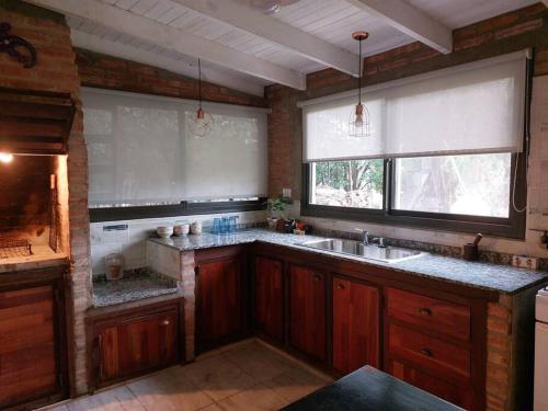 多洛雷斯镇Cardozo House, casa de campo的厨房配有木制橱柜、水槽和2扇窗户。
