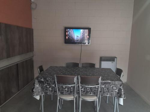 玛利亚镇CASA QUINTA La Donna con DESAYUNO的餐桌、椅子和墙上的电视