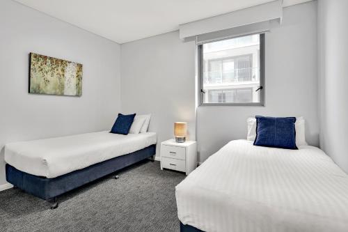 悉尼North Sydney Large Two Bedroom MIL2302的一间卧室设有两张床和窗户。