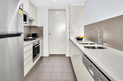 悉尼North Sydney Large Two Bedroom MIL2302的白色的厨房配有水槽和冰箱
