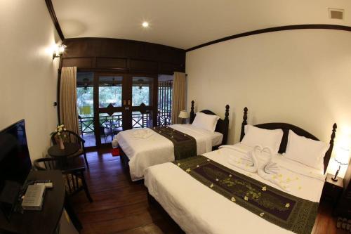 巴色Phubachiang Golf and Resort Pakse的酒店客房设有两张床和电视。