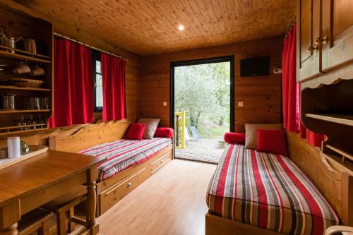 沃格于埃Roulottes et Cabanes de Saint Cerice的一间设有两张床铺的小屋,配有红色窗帘