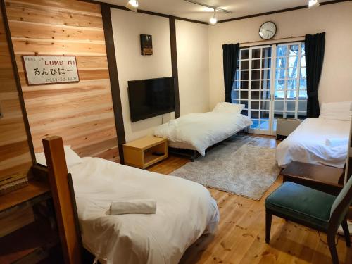 白马村Hakuba Matata Apartment的客房设有两张床和一台平面电视。