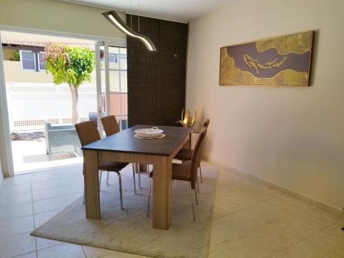 卡勒达德福斯特Spacieux Duplex Casa Maya Caleta de Fuste的一间带木桌和椅子的用餐室