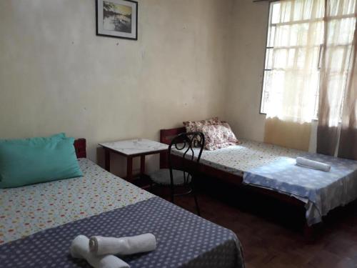 圣胡安CVNB guesthouse的客房设有两张床、一张桌子和一扇窗户。