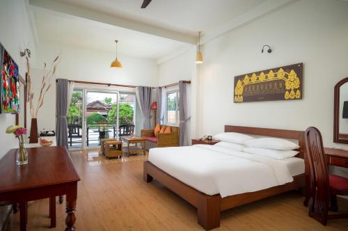 暹粒Sala Siem Reap Hotel的一间卧室配有一张床、一张桌子和一张桌子