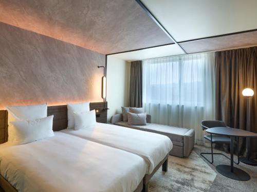 伯尔尼Novotel Bern Expo的酒店客房设有两张床和一张桌子。