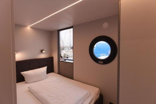 弗伦斯堡Hausboot Fjord Meeresbrise mit Dachterrasse in Flensburg的一间小卧室,配有床和窗户