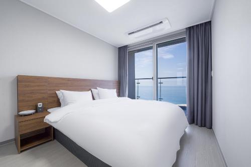 江陵市Gangneung Chonpines Ocean Suites Hotel的一间卧室设有一张大床和一个大窗户