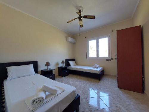卡图亚该亚Lakkopetra Beach House的一间卧室配有两张床和吊扇