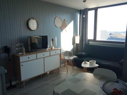 贝斯和圣阿纳斯泰斯Chez Loïc et Mélanie的客厅配有电视、沙发和时钟