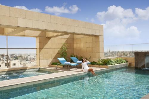 安曼费尔蒙特安曼酒店的坐在建筑物游泳池边的女人