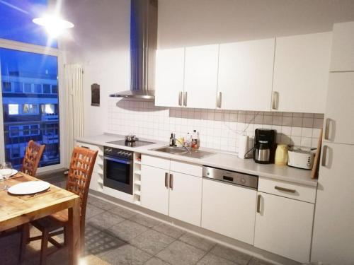 不莱梅Penthousewohnung 126 qm Bremen Innenstadt+ Dachterrasse的厨房配有白色橱柜、桌子和窗户。