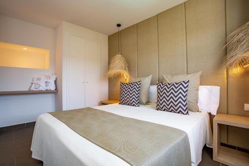 普拉亚登博萨米格霍恩伊维萨套房水疗酒店的一间卧室配有一张大床和枕头
