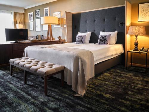拉斯罗普兰德果霍特韦酒店的酒店客房设有一张大床和长凳。