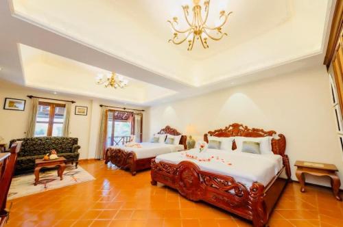 琅勃拉邦Villa Deux Rivieres双河别墅酒店的一间卧室配有两张床、一张沙发和一个吊灯。