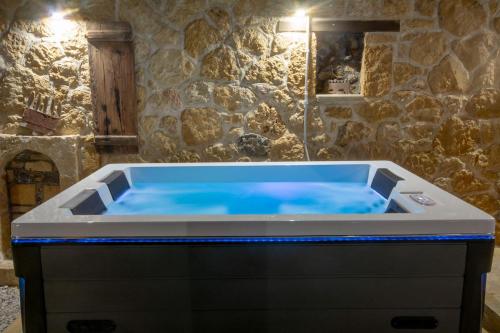 基萨莫斯Pamelas House with Jacuzzi的石头浴室内带蓝色灯光的热水浴池
