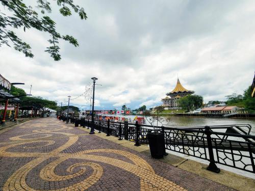 古晋Upspot Kuching Waterfront Premium Hostel的水体旁边的走道,有一座建筑