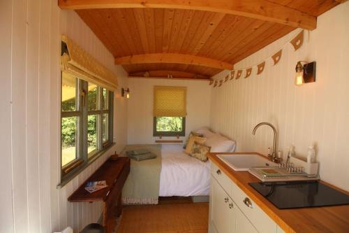 黑尔斯沃思The Warren - Cosy Shepherds Hut in beautiful wild meadow的卧室配有床和盥洗盆