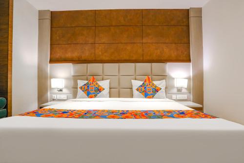新德里FabHotel Hexa Chhatarpur的卧室配有一张带彩色枕头的大型白色床。