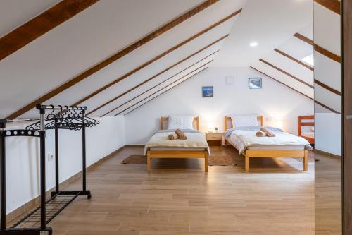 GračacSOKOL - Secret forest house的阁楼间设有2张床,配有白色的墙壁和木地板