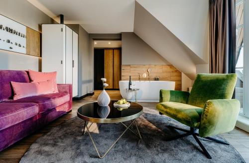 提努姆Relais & Châteaux Landhaus Stricker, Hotel des Jahres 2023的客厅配有紫色和绿色的椅子和一张桌子