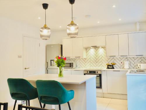 法恩伯勒Luxurious Detached Bungalow with Private Parking的厨房配有白色橱柜和一张带绿色椅子的桌子