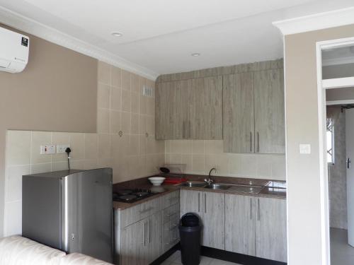 哈拉雷2 bedroomed apartment with en-suite and kitchenette - 2065的厨房配有木制橱柜和冰箱。