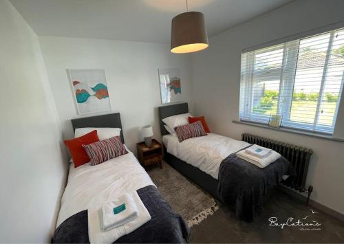 布里克瑟姆Stylish Brixham home, sleeps 7, parking & garden的一间卧室设有两张床和窗户。