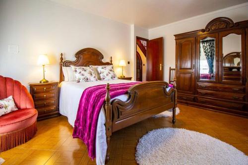 Vitorino das DonasCasa da Garrida的一间卧室配有一张大床和一张红色椅子