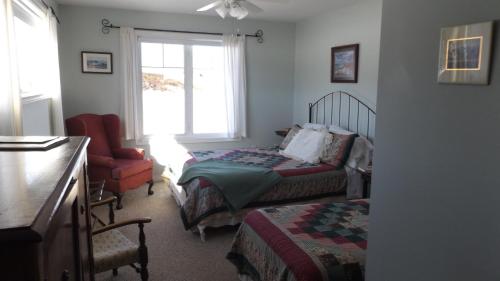 Harmony Junction约翰逊岸边酒店的一间卧室设有两张床、一把椅子和一个窗户。
