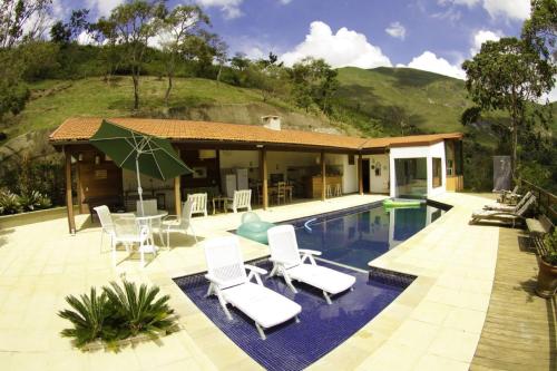 伊泰帕瓦Pousada Alto Itaipava的别墅 - 带带椅子的游泳池和房屋