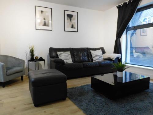 曼彻斯特2 Bed Modern Apartment Manchester City Centre的客厅配有黑色沙发和椅子